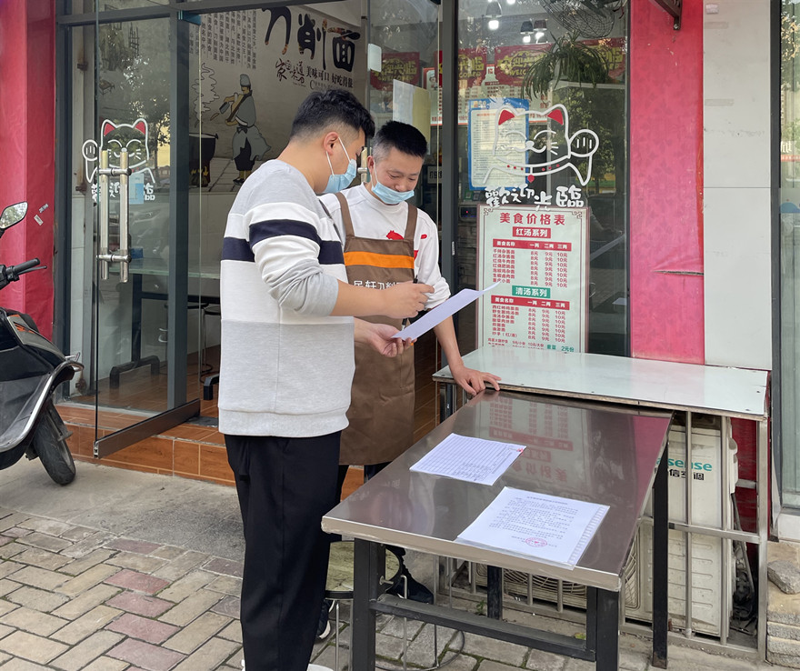 事情职员向商家宣传和发放疫情防控相关资料2_副本
